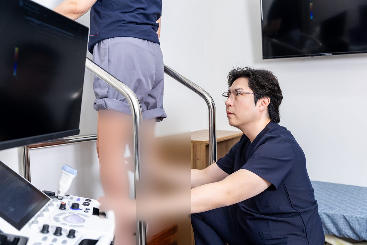 김서전 대표원장이 서 있는 환자의 다리를 도플러 초음파로 검사하는 모습