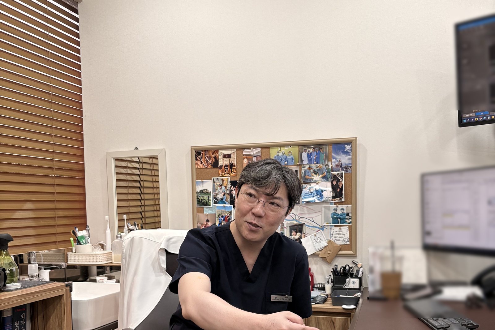 의사가 진료실에서 책상 위 서류를 가리키며 상담하는 모습.