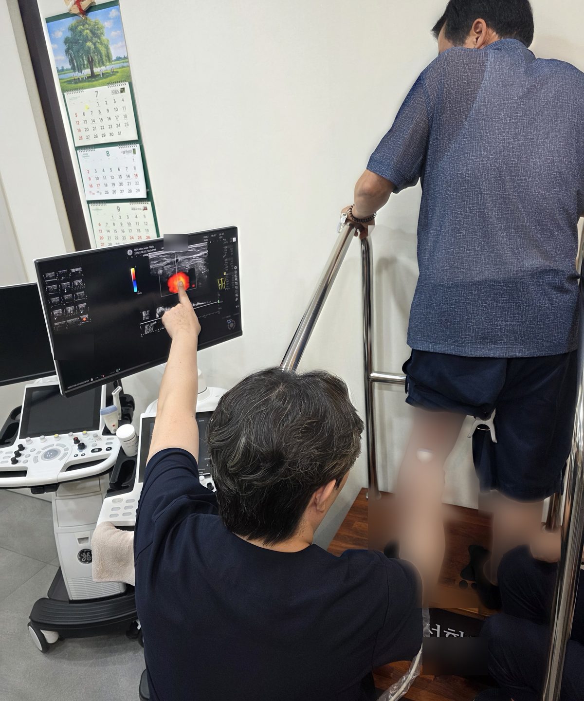 의료진이 초음파 장비로 서 있는 환자의 다리 혈관을 검사하는 모습.