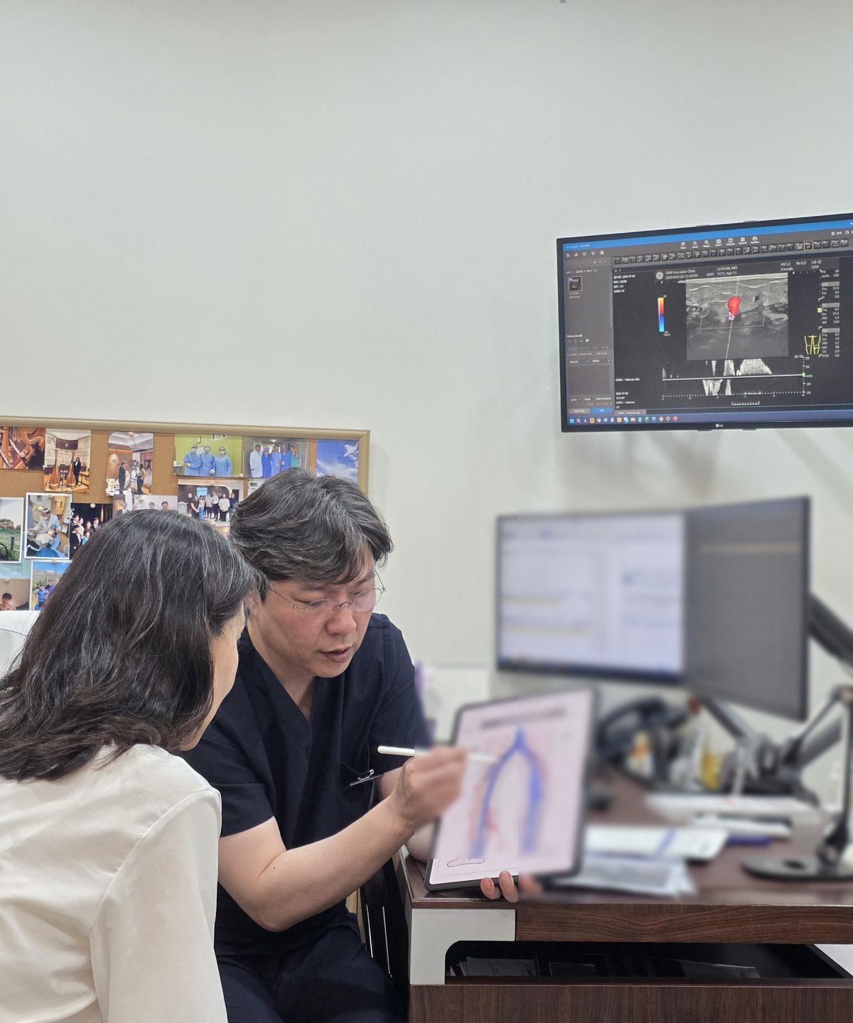 의사가 태블릿으로 혈관 구조와 검사 결과를 보여주며 환자에게 상담하는 진료 장면.