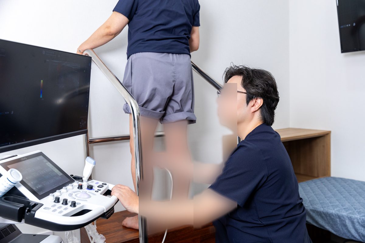 김서전 대표원장이 서 있는 환자의 다리를 도플러 초음파로 검사하는 모습