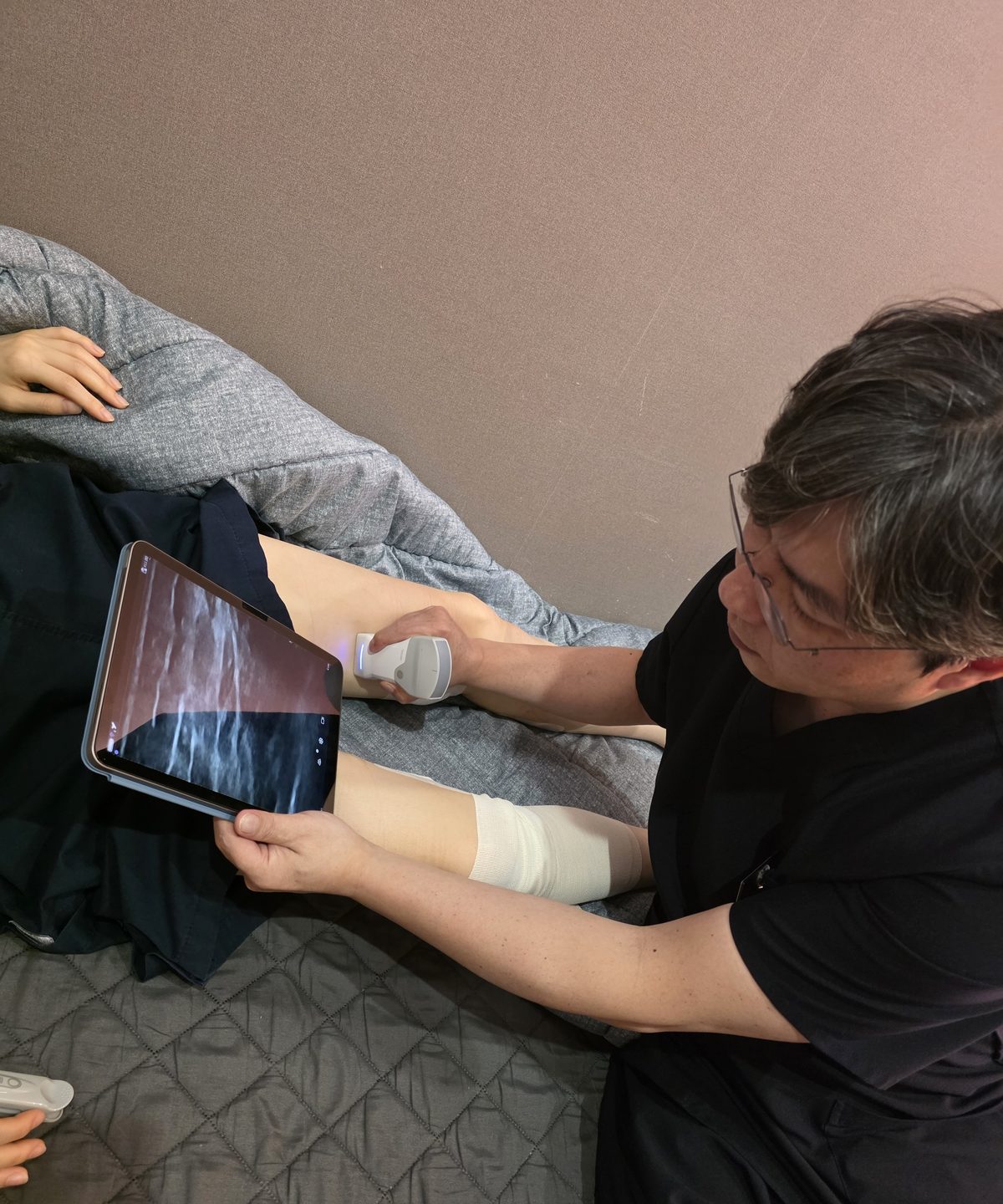 김서전 대표원장이 휴대용 초음파 검사기로 환자의 다리를 검사하는 모습