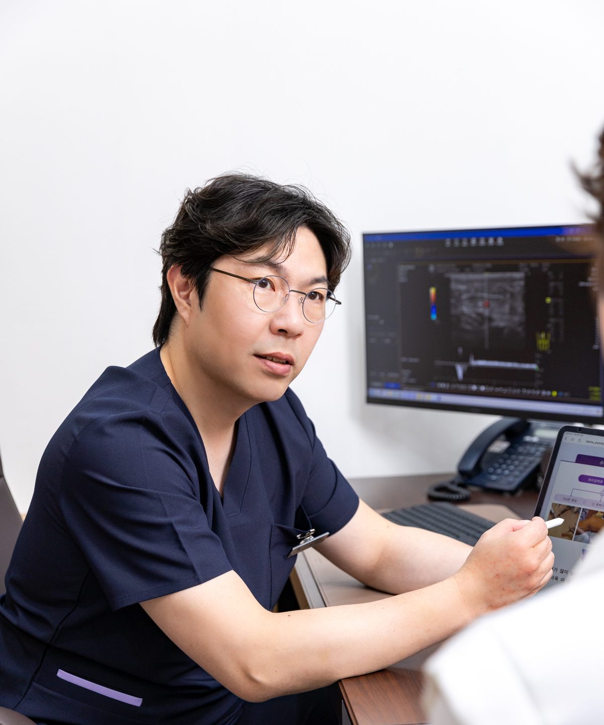김서전 대표원장이 초음파 화면 옆에서 환자에게 설명하는 모습