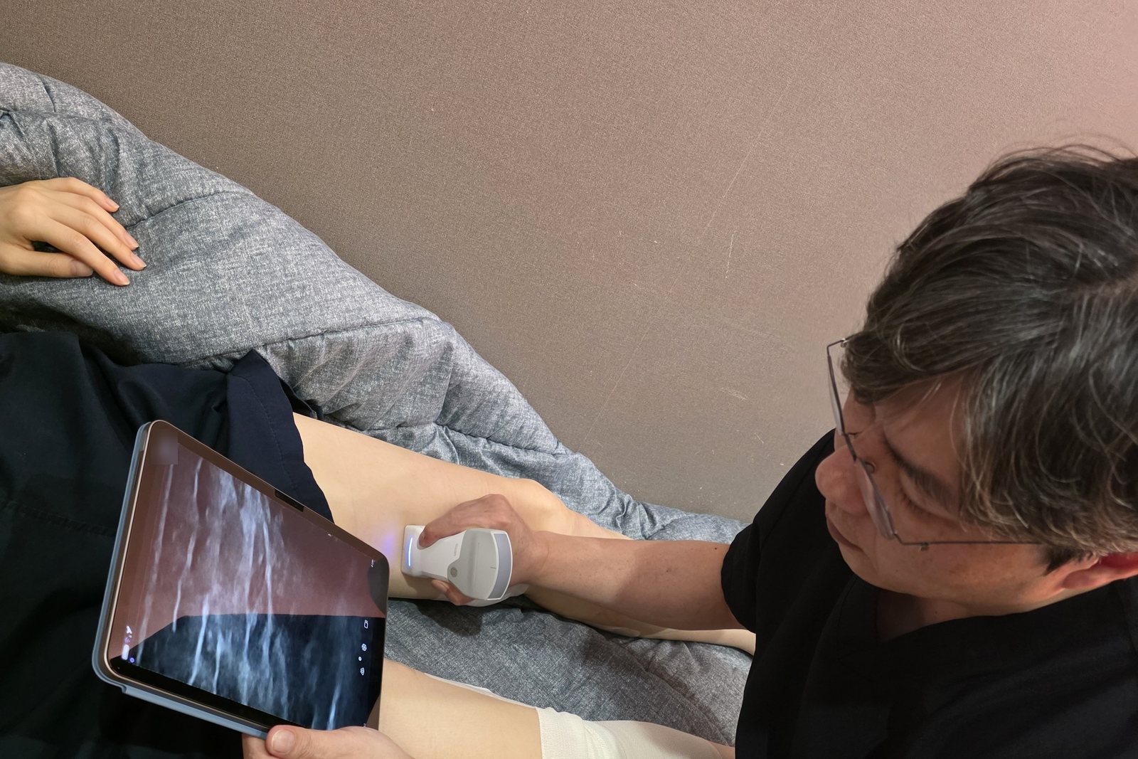 김서전 대표원장이 휴대용 초음파 검사기로 환자의 다리를 검사하는 모습